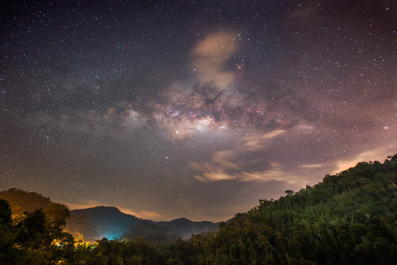 银河中心悬在山谷与水库上方，山脚有零星灯火。