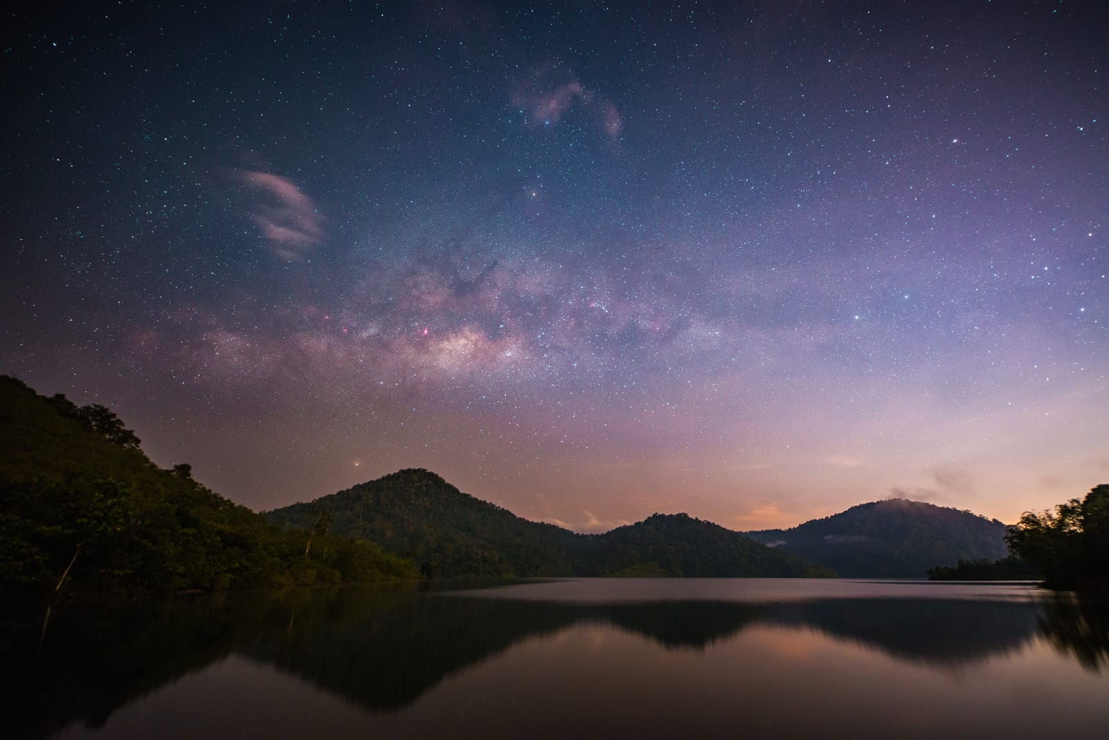 银河横过湖面上空，群山与星空倒映在水里。